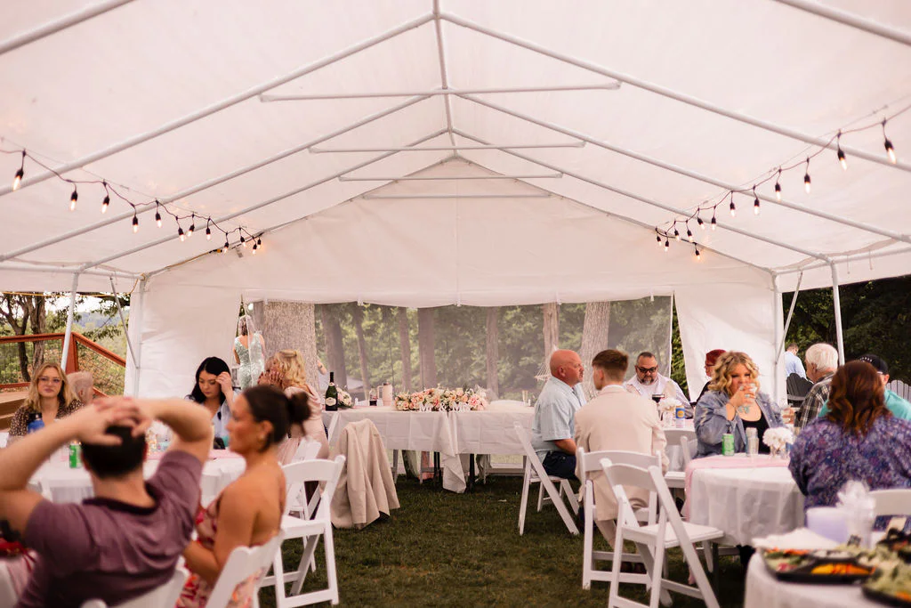 Guests dining under a light-filled reception tent at Pondside